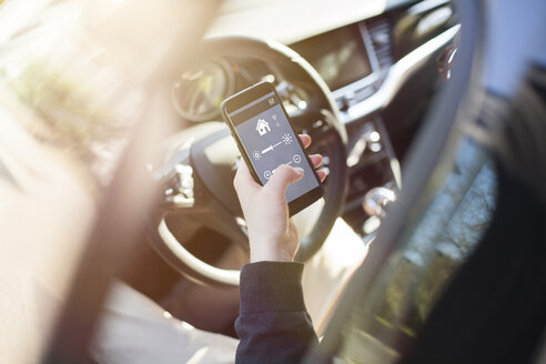 Man in car adjusting devices at home via smartphone - NAF00085