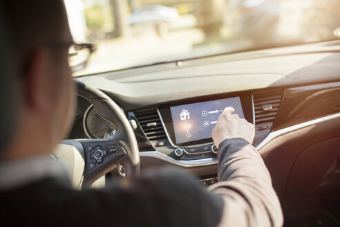 Man in car adjusting devices at home via smartphone - NAF00087