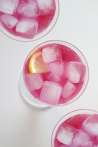 Gläser mit dem Cocktail 'Pink Flamingo' mit Eiswürfeln und Zitronenscheibe, lizenzfreies Stockfoto