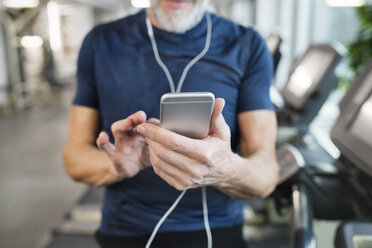 Älterer Mann benutzt Smartphone im Fitnessstudio - HAPF01652