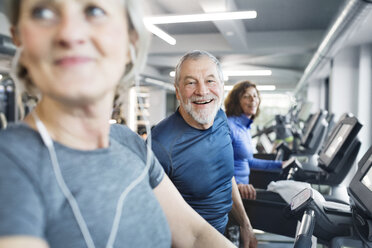 Gruppe von fitten Senioren auf Laufbändern im Fitnessstudio, Mann lächelt - HAPF01658