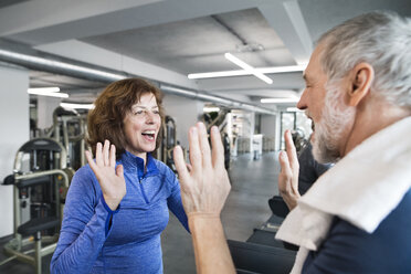 Glücklicher älterer Mann und Frau, die sich nach dem Training im Fitnessstudio die Hände reichen - HAPF01664