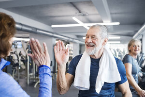 Glücklicher älterer Mann und Frau, die sich nach dem Training im Fitnessstudio die Hände reichen - HAPF01665