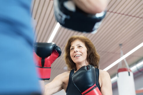 Fit senior woman boxing with her coach - HAPF01682
