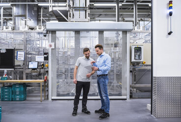 Two men with tablet talking in factory shop floor - DIGF02338