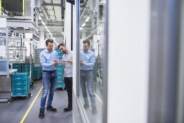 Two men with tablet talking in factory shop floor - DIGF02340