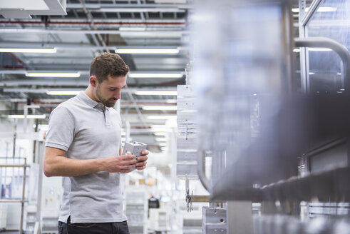 Man with tablet in factory shop floor examining products - DIGF02345