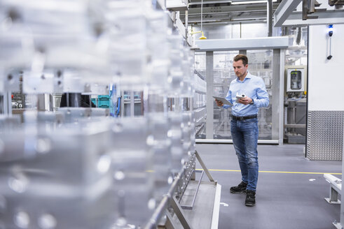 Man with tablet in factory shop floor examining products - DIGF02346