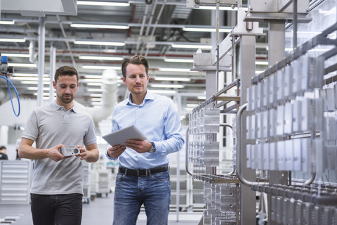 Two men with tablet talking about a product in factory shop floor stock photo