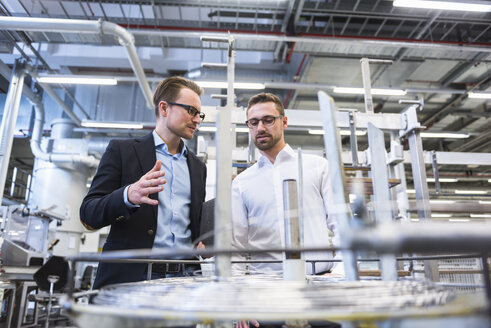 Two men talking in factory shop floor - DIGF02369