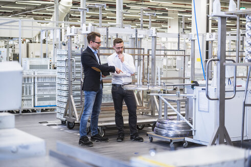 Two men talking in factory shop floor - DIGF02371