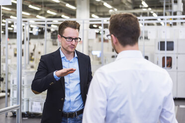 Two men talking in factory shop floor - DIGF02375