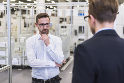 Two men talking in factory shop floor - DIGF02376