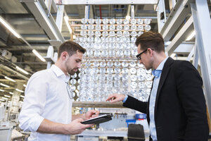 Zwei Männer in einer Fabrikhalle, die Produkte prüfen - DIGF02387