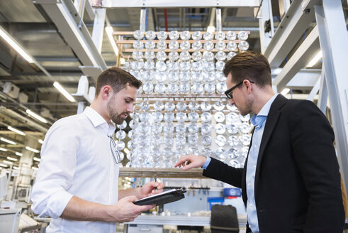 Zwei Männer in einer Fabrikhalle, die Produkte prüfen - DIGF02387