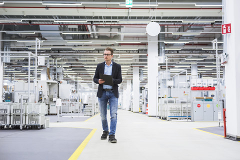 Man walking in factory shop floor taking notes stock photo