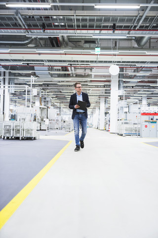 Man walking in factory shop floor taking notes stock photo