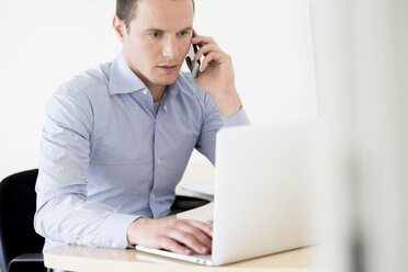 Geschäftsmann am Telefon mit Laptop - FMOF00244