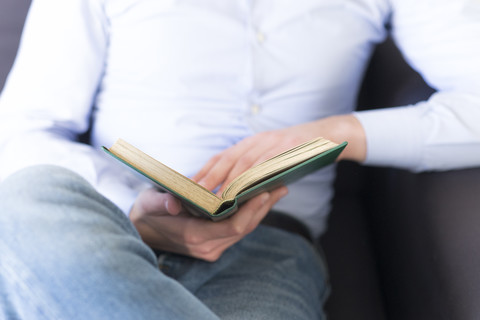 Close-up of man on couch reading book stock photo