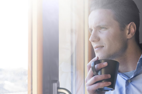 Geschäftsmann mit Tasse Kaffee schaut aus dem Fenster, lizenzfreies Stockfoto