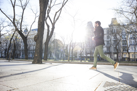 Junger Mann am Telefon beim Spaziergang in der Stadt, lizenzfreies Stockfoto