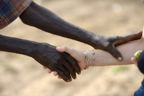 Burkina Faso, alter afrikanischer Mann schüttelt Hände mit weißer Frau, lizenzfreies Stockfoto