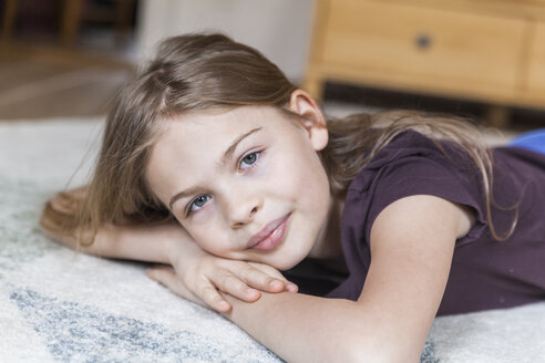 Porträt eines Mädchens, das zu Hause auf einem Teppich liegt - TCF05392