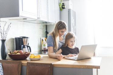 Mutter und Tochter benutzen Laptop in der Küche - TCF05399