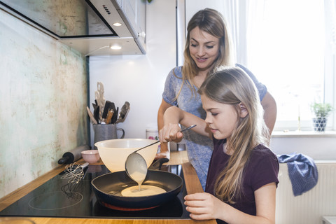 Mutter und Tochter backen Pfannkuchen in der Küche, lizenzfreies Stockfoto