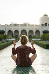 Marokko, Marrakesch, Tourist sitzt auf dem Boden in einem Innenhof und macht Yoga - KKAF00789