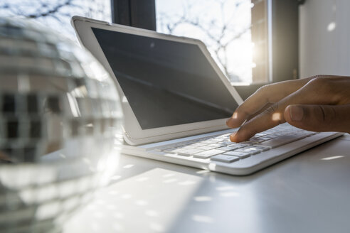 Nahaufnahme einer männlichen Hand, die auf einem Tablet am Fenster tippt - SBOF00422