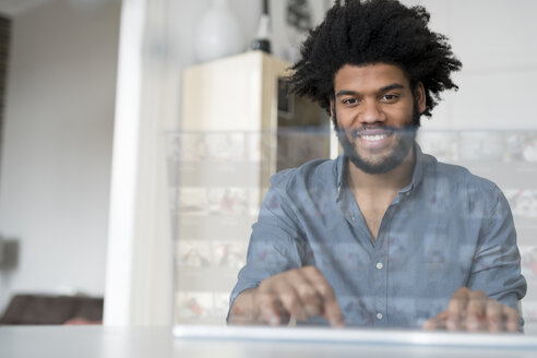 Lächelnder Mann arbeitet zu Hause an einem futuristischen Bildschirm - SBOF00449