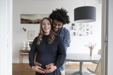 Lächelndes schwangeres Paar im Wohnzimmer - SBOF00455