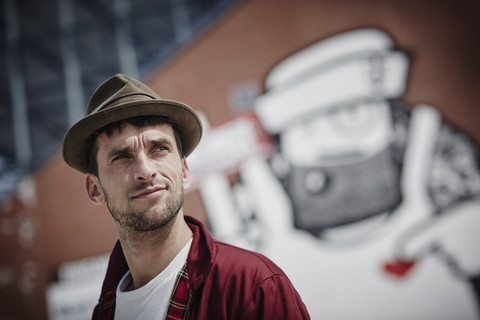 Deutschland, Hamburg, St. Pauli, Mann mit Hut vor einem Graffiti stehend, lizenzfreies Stockfoto