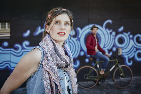 Germany, Hamburg, St. Pauli, Young woman and man on bicycle standing in front of graffiti stock photo