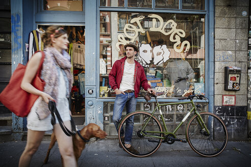 Deutschland, Hamburg, St. Pauli, Mann mit Fahrrad wartet vor einem Vintage-Laden, Frau mit Hund kommt heraus - RORF00823