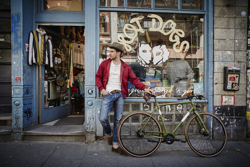 Germany, Hamburg, St. Pauli, Man with bicycle waiting in front of vintage shop - RORF00824