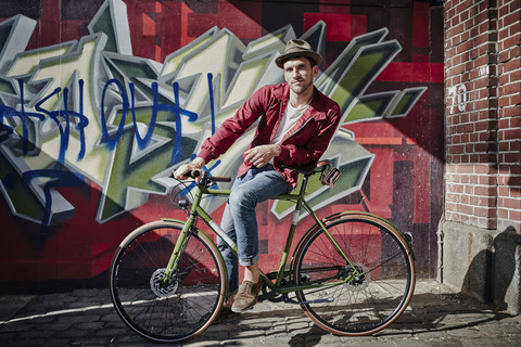 Deutschland, Hamburg, St. Pauli, Mann sitzt auf Fahrrad vor Graffiti, lizenzfreies Stockfoto