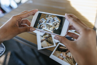 Woman's hands taking picture of instant photos of herself with cell phone - KIJF01452