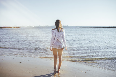 Rückenansicht einer Frau am Strand mit Blick auf das Meer, lizenzfreies Stockfoto