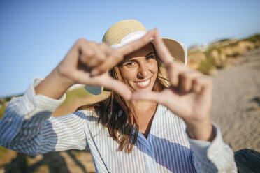 Portrait of smiling young woman making finger frame on the beach - KIJF01466