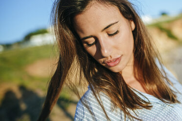 Porträt einer jungen Frau mit geschlossenen Augen im Sonnenlicht - KIJF01467
