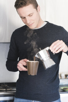 Mann gießt in der Küche heißen Espresso in eine Tasse - FMOF00253