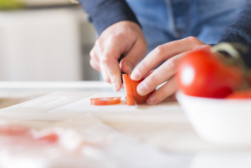 Männerhände, die eine Tomate schneiden - FMOF00256