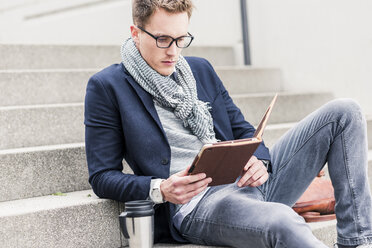 Young businessman sitting on stairs, using digital tablet - UUF10599