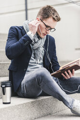 Young businessman sitting on stairs, using digital tablet - UUF10601