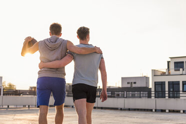 Freunde spielen Basketball bei Sonnenuntergang auf einer Dachterrasse - UUF10634