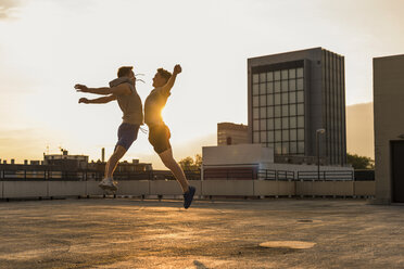 Friends jumping for joy at sunset - UUF10639