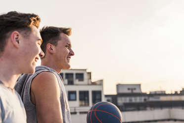 Friends playing basketball at sunset on a rooftop - UUF10640