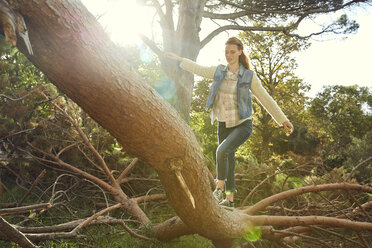 Junge Frau balanciert auf einem Baumstamm - SRYF00438